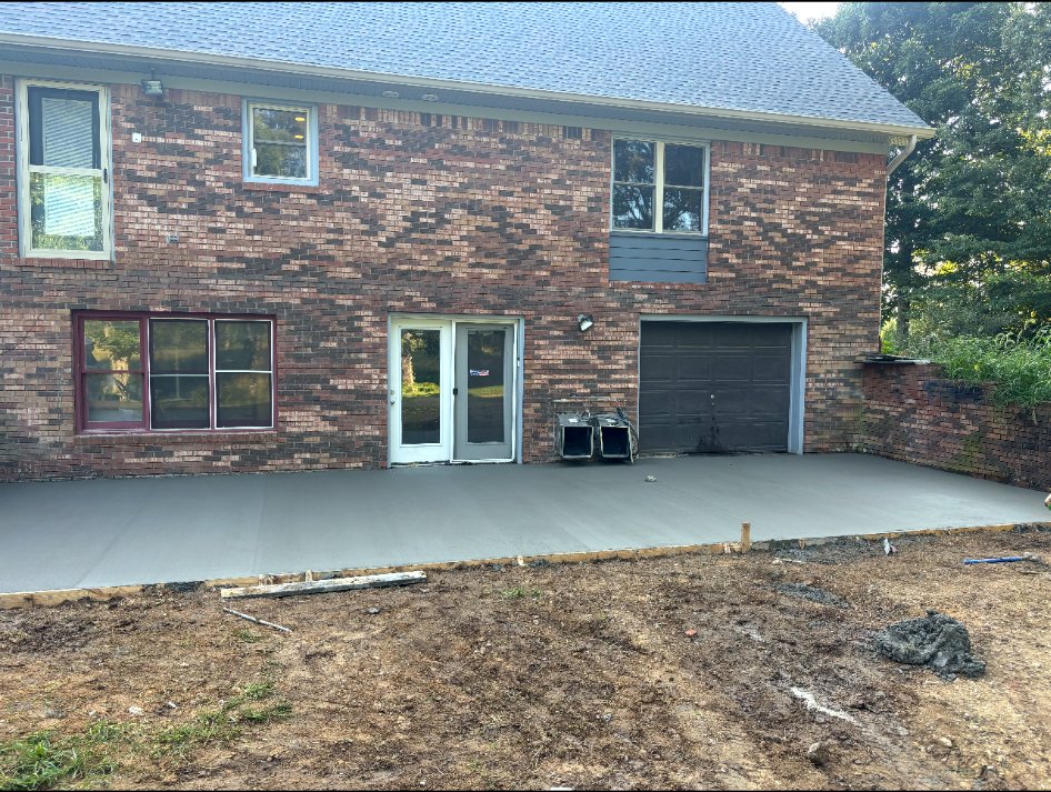 New concrete patio along the back of a brick home.